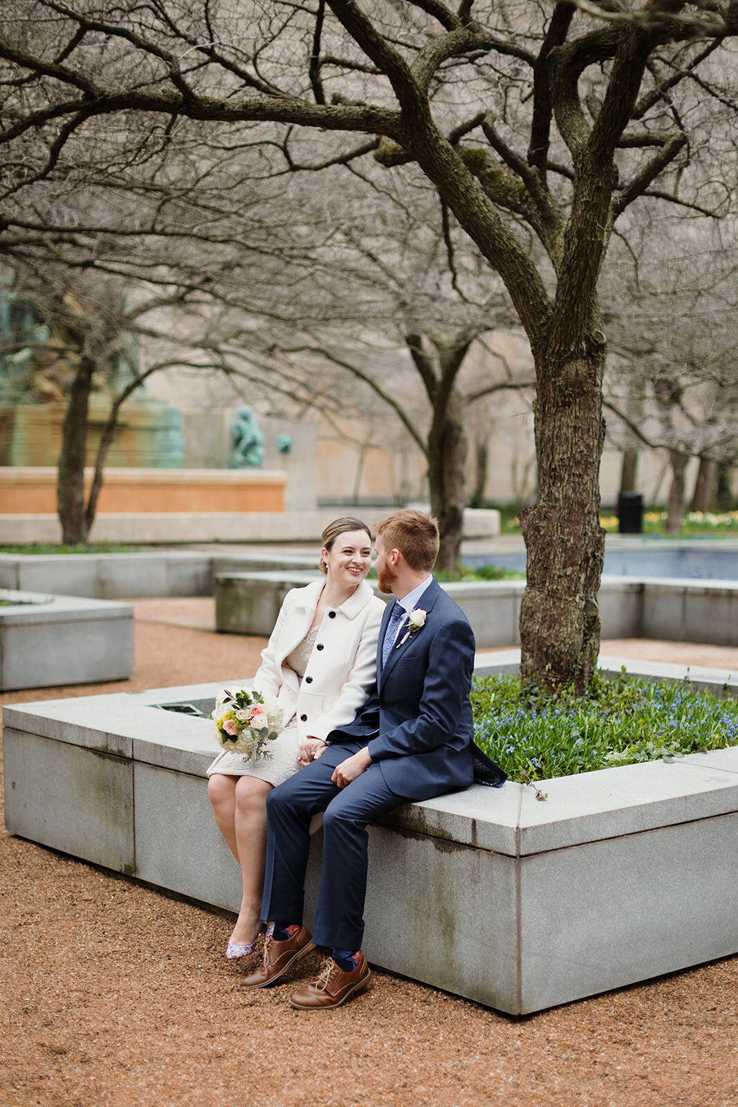 Just Married photo session  couple sits on a large flower box and they laugh and smile