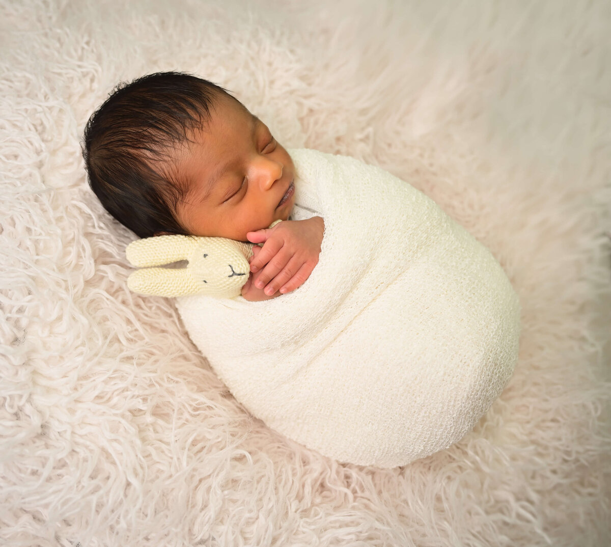Kitsap Peninsula  in home newborn session with baby wrapped in white and holding small lovey.