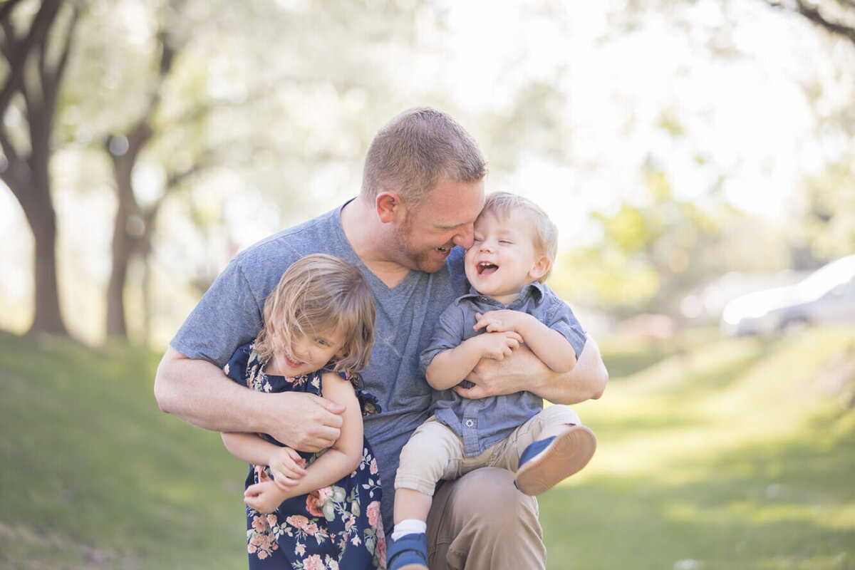 a man kneeling playing with two toddlers