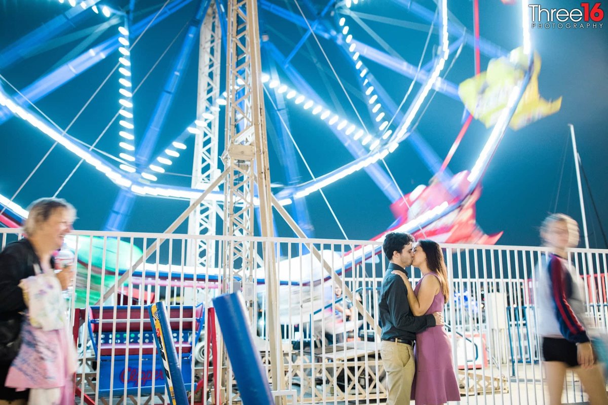 Engaged Couple share a kiss in front of the Balboa Fun Zone Ferris Wheel