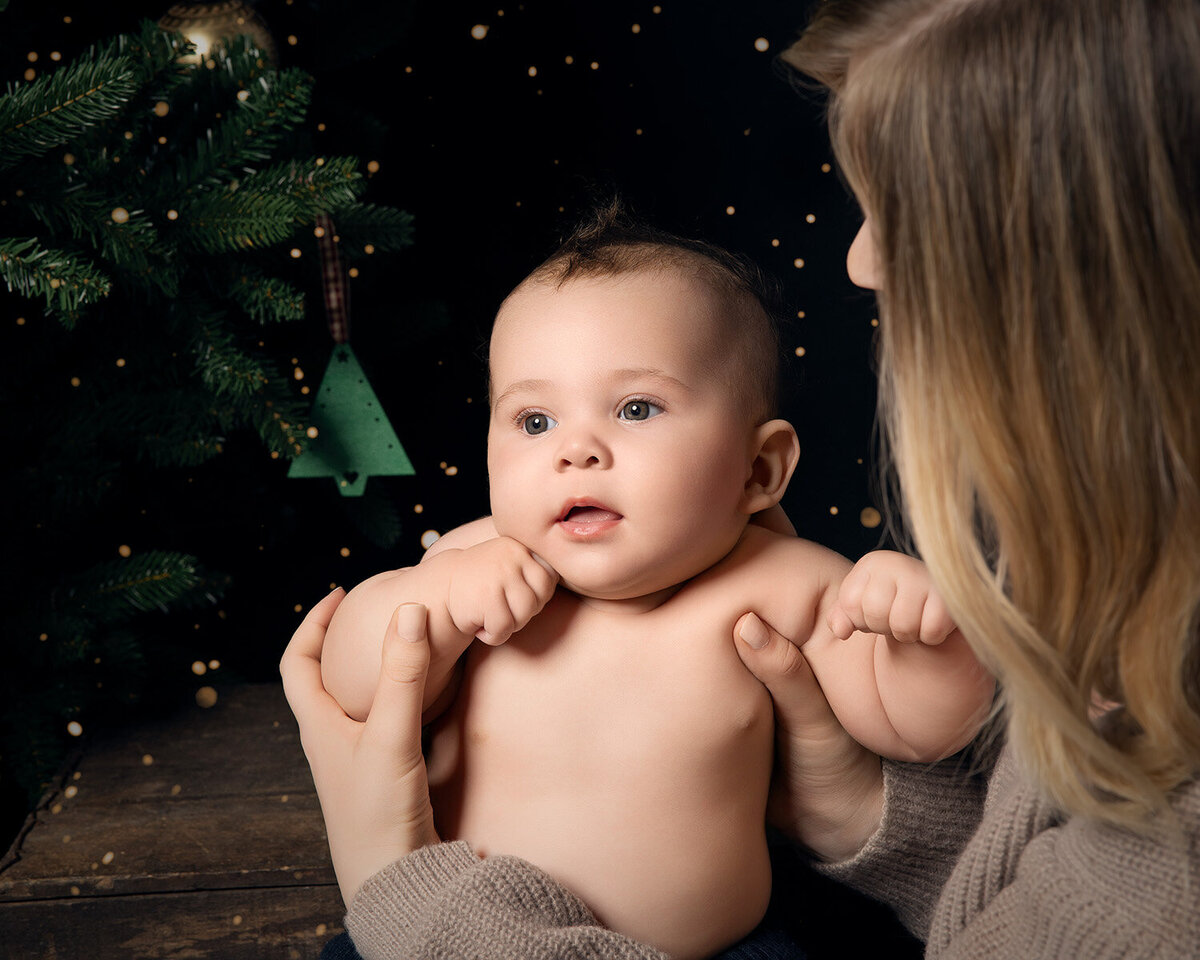Image of a baby and Mum on a Christmas tree backdrop in the studio. Taken by Norwich portrait photographer Claire Howes. Christmas Mini Sessions Norwich.