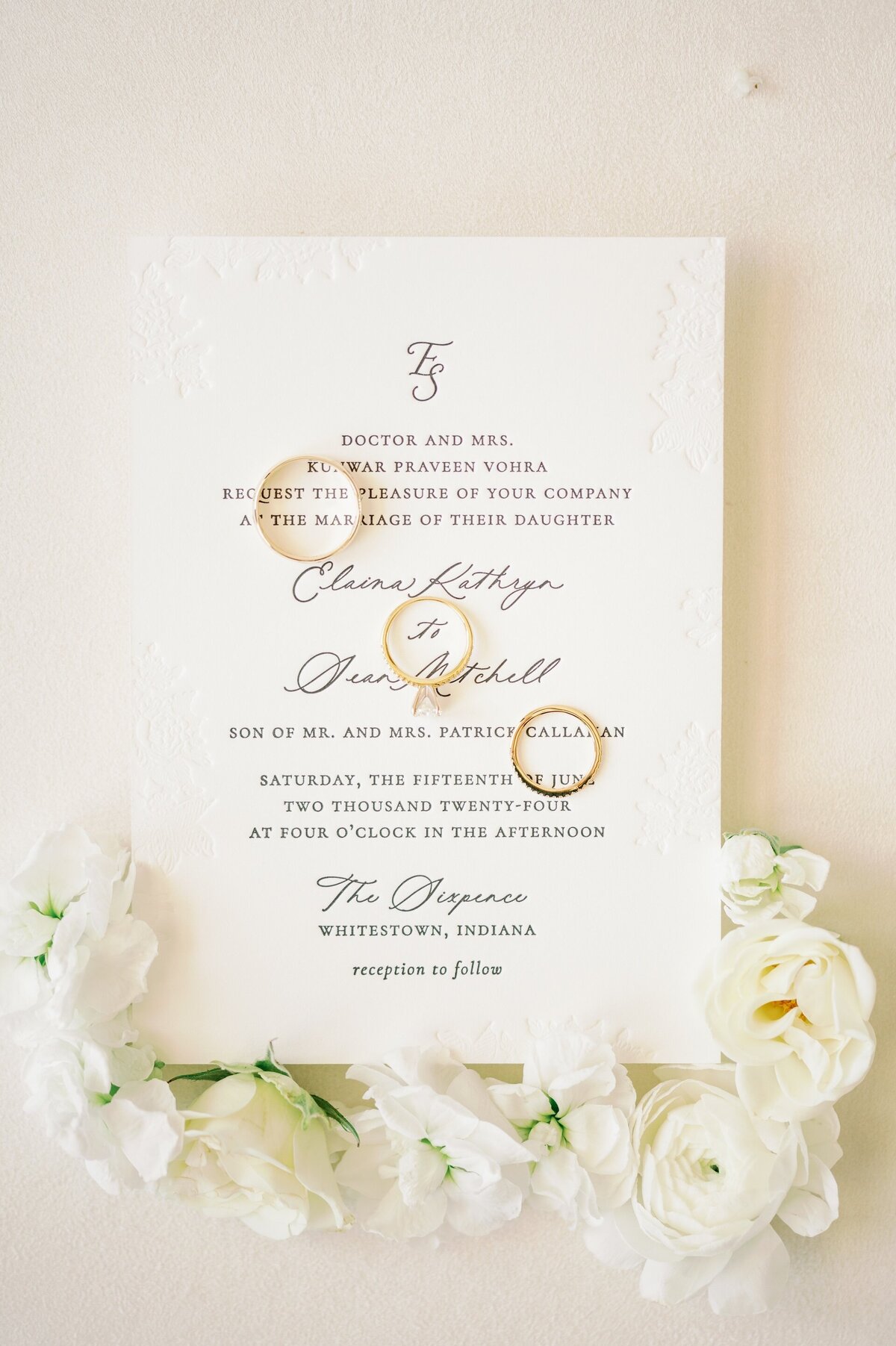 wedding rings sitting on a wedding invitation