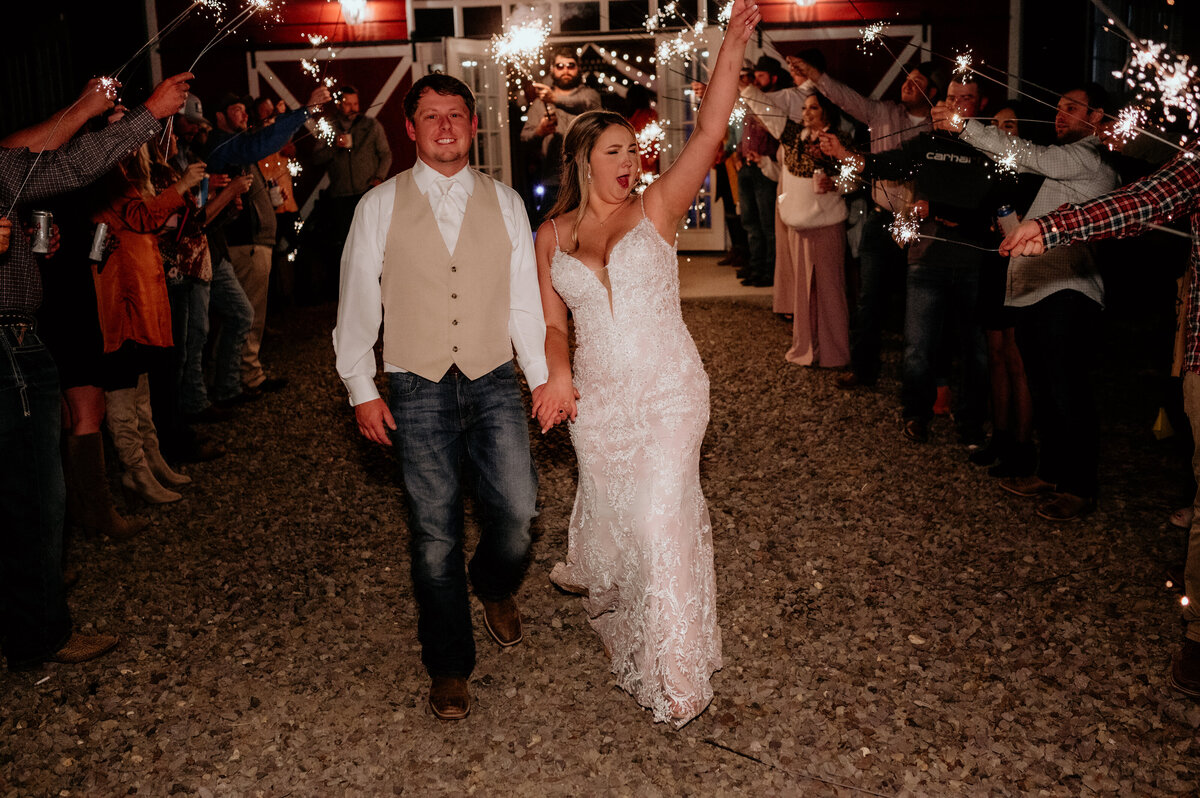 grand exit at the end of little rock wedding with bride and groom walking through sparklers while cheering