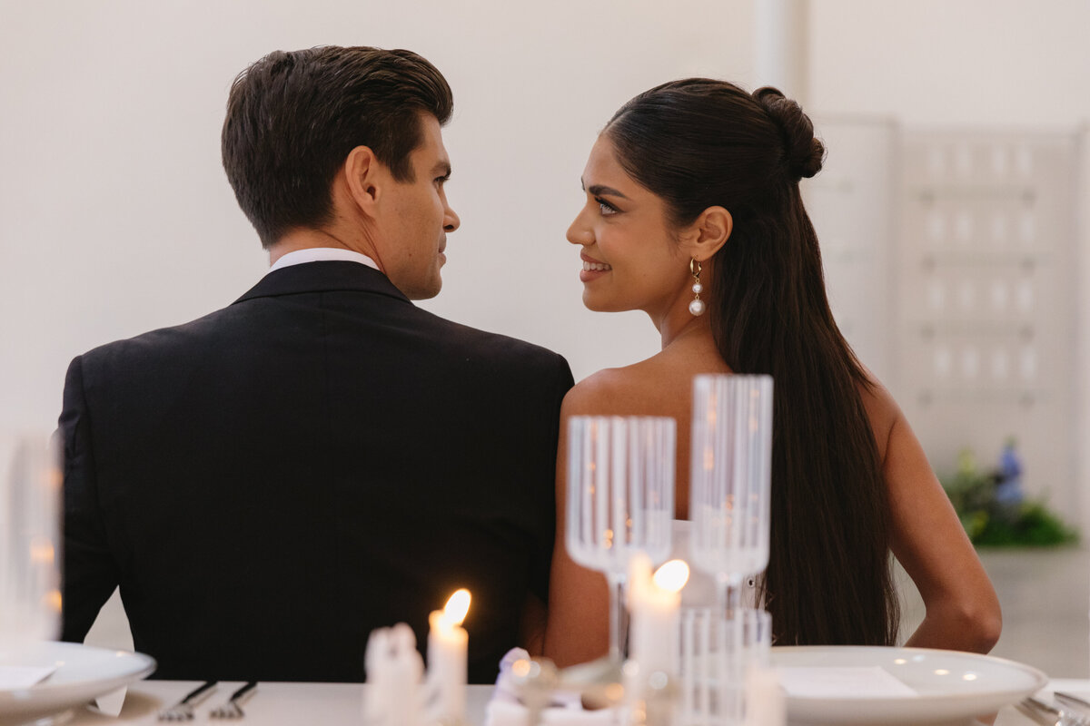 Close-up of minimal wedding table details with candles and sculptural florals.