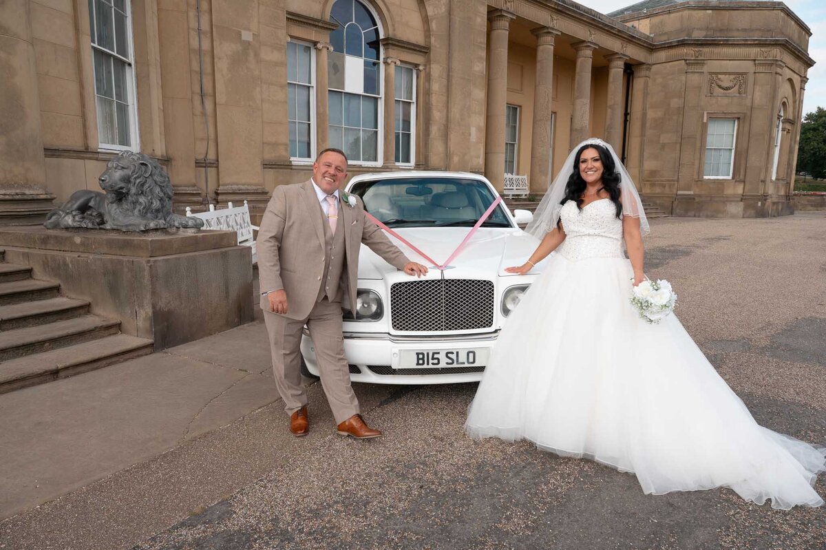 Bride and groom outside Heaton Park Pavilion with wedding car – classic portrait.