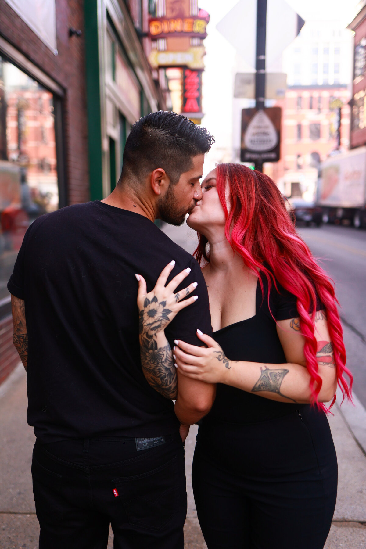 man and woman wearing black clothes holding arms and kissing in nashville tennessee by amanda richardson photography