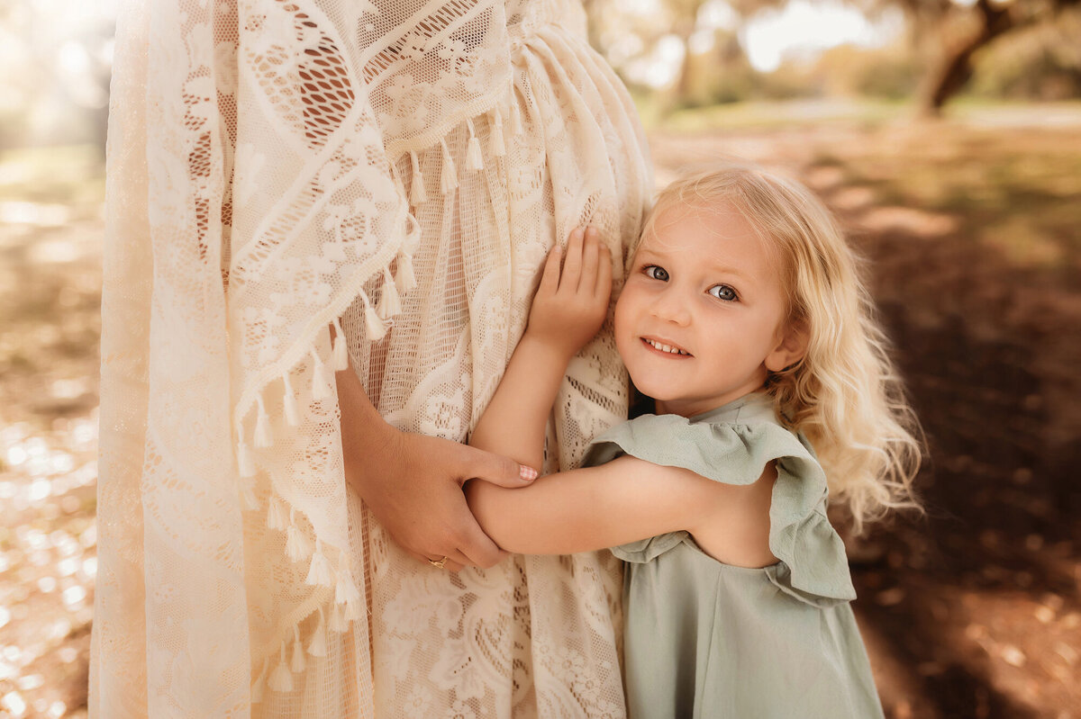 Little girl hugs her mama's pregnant belly during Maternity Photoshoot in Charleston.