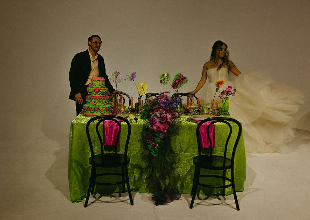 A wedding couple standing on either side of a reception table.