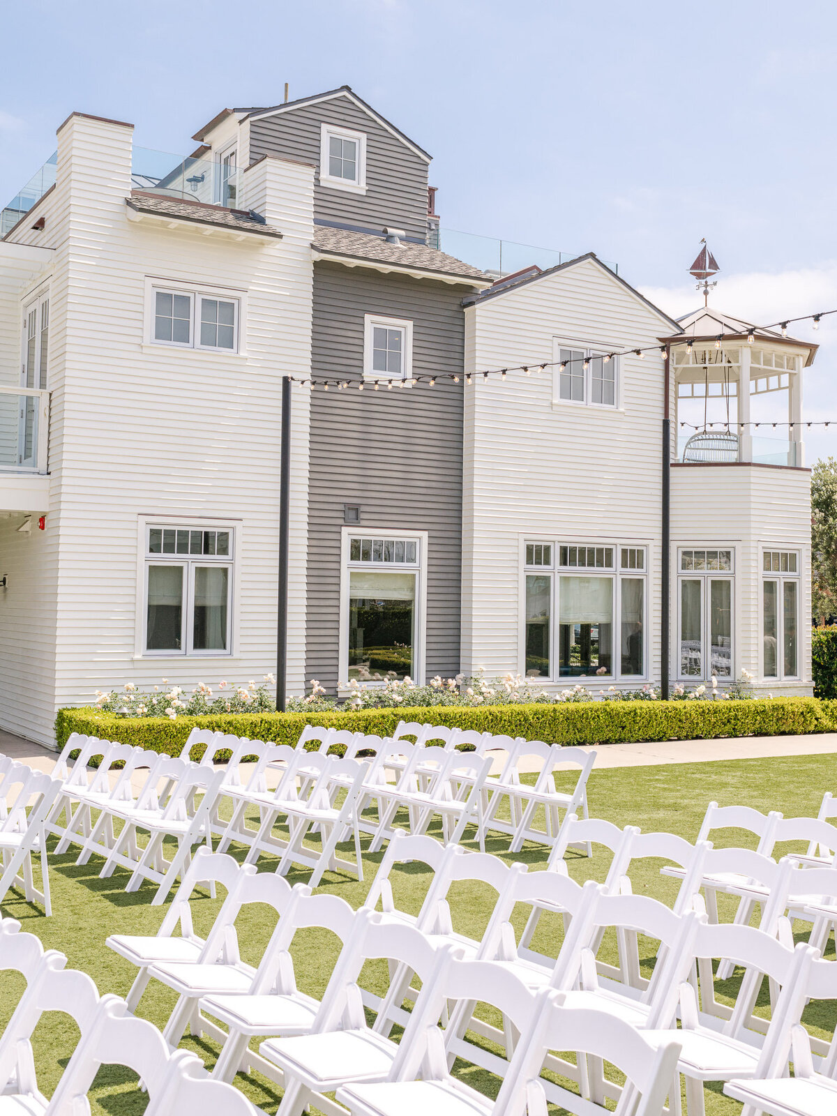 Elegant outdoor wedding ceremony setup with white chairs and string lights at Lido House, Newport Beach