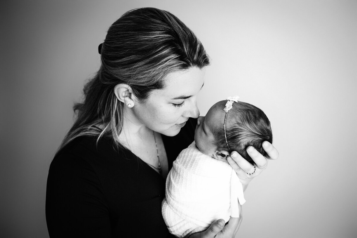 Black and white portrait of mom holding newborn baby girl in arms and rubbing noses in Jacksonville, Florida.