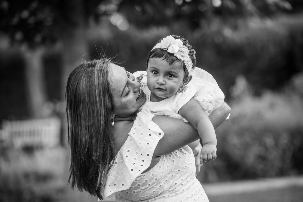 A mom holding a baby up and smiling