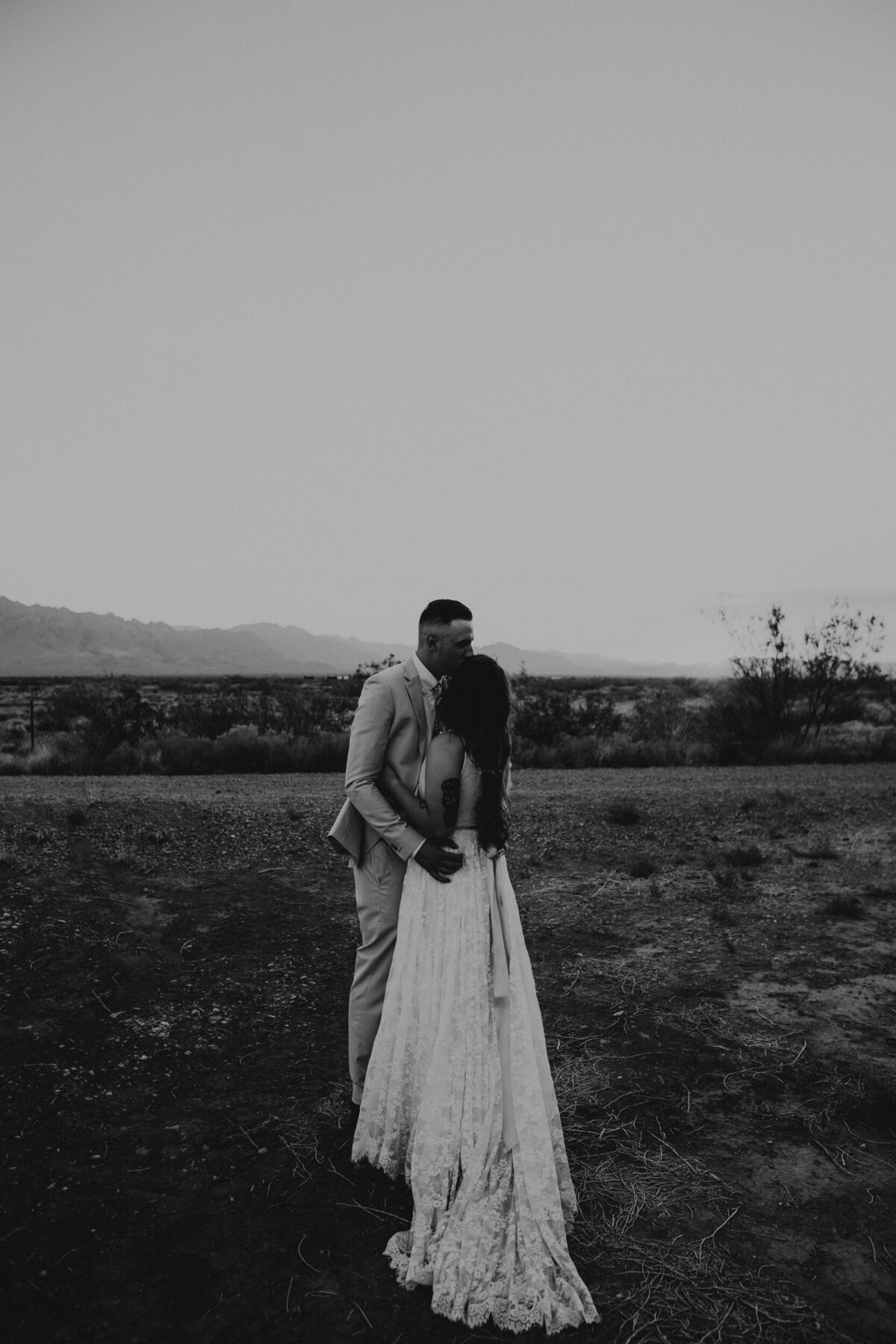 bride and groom hugging each other at sunset