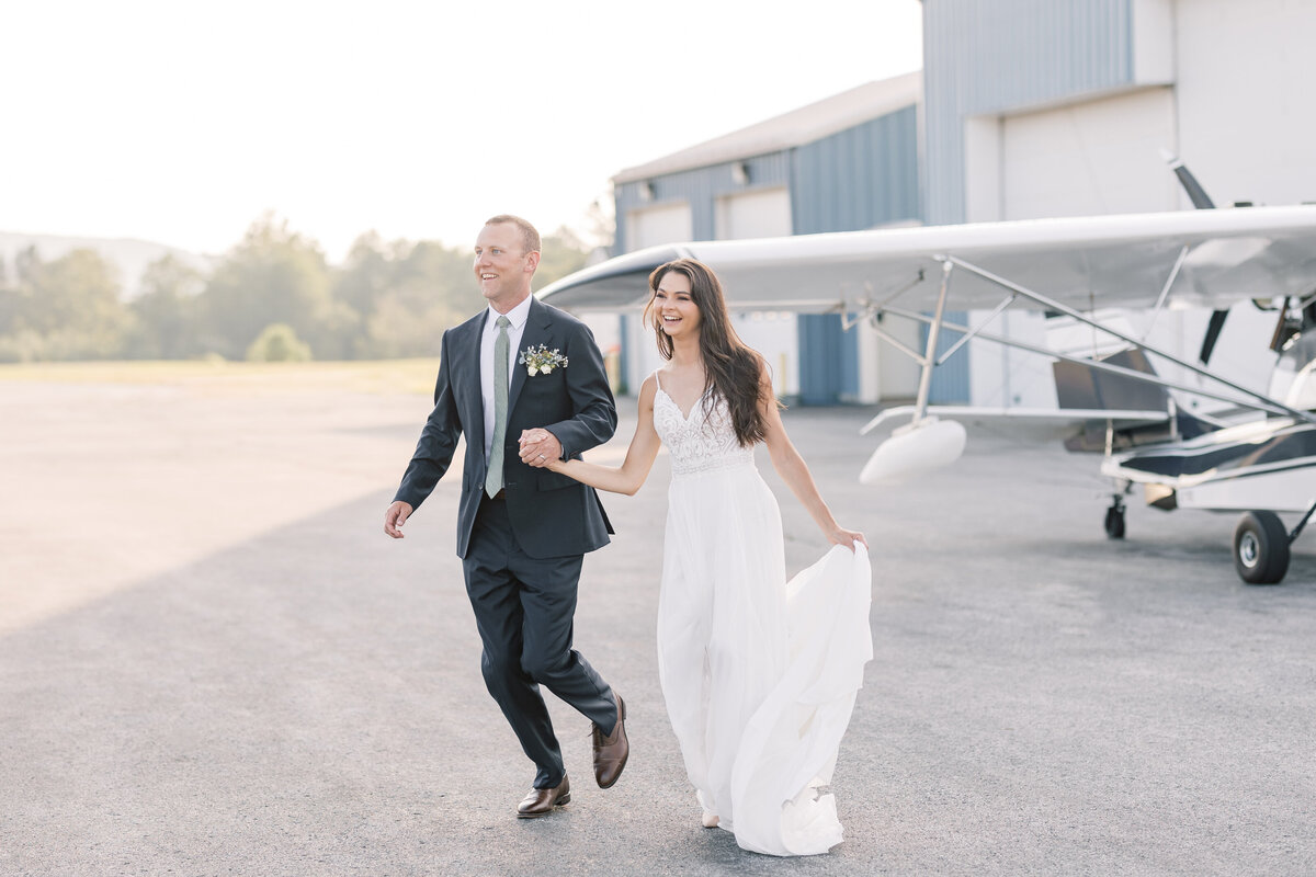 A just married couple running away from their airplane after they landed at a private airport on their wedding day.