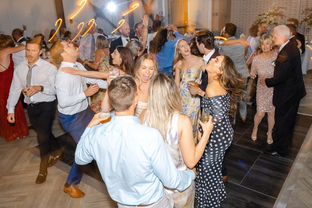 Wedding guests fill the dance floor, celebrating with drinks, music, and laughter at a high-energy Lido House reception in Newport Beach