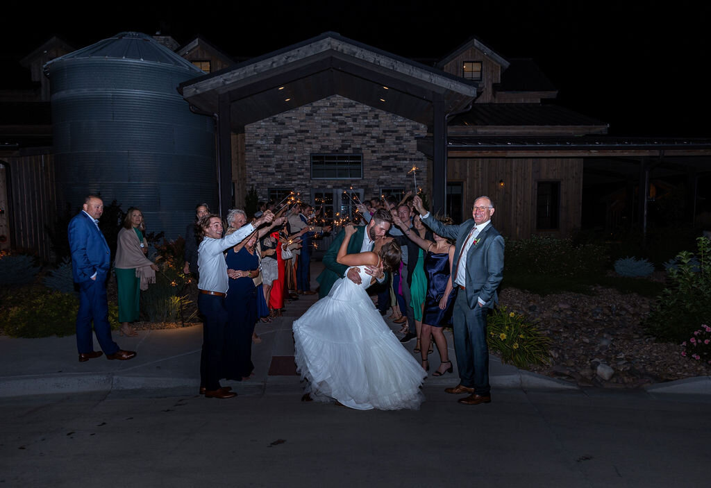 Bride and groom share a kiss after their grand exit from their wedding surrounded by their guests.