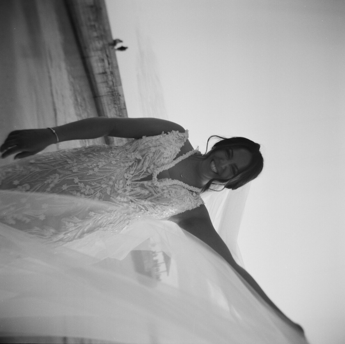 Black and white photo of a smiling bride at sunset, her veil flowing in the breeze — captured in a candid wedding photography style — Carmel wedding photography by Kate Winters Photography.