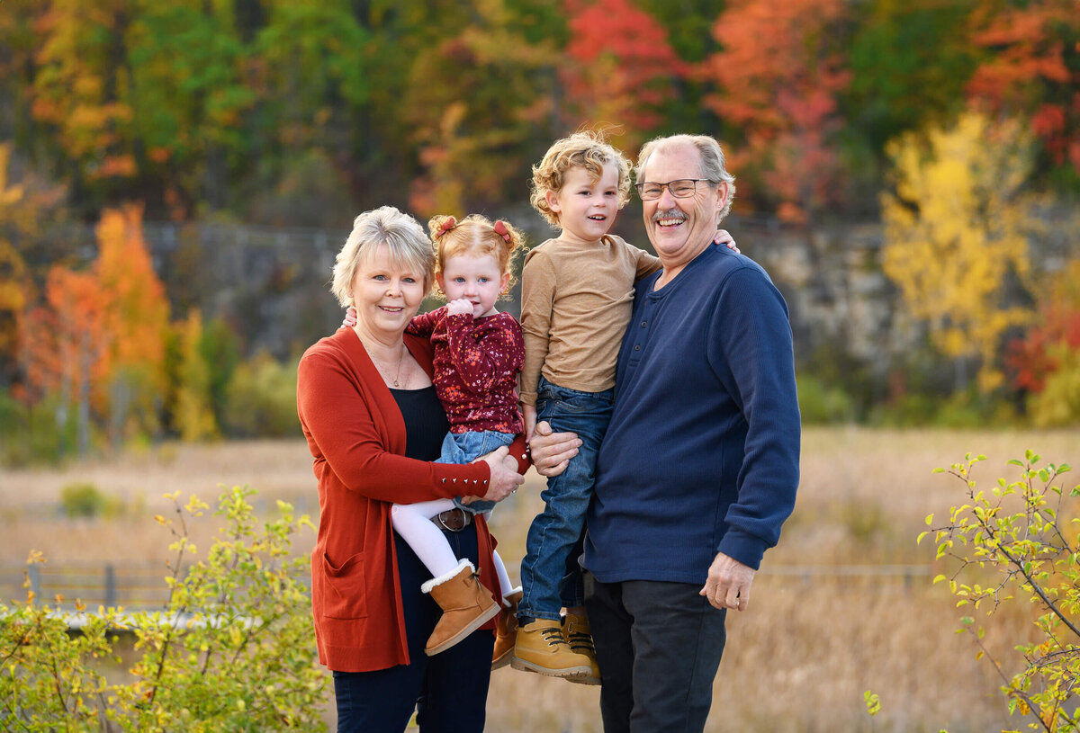 Grandma and Grandpa holding their grandson and granddaughter for their fall family photos