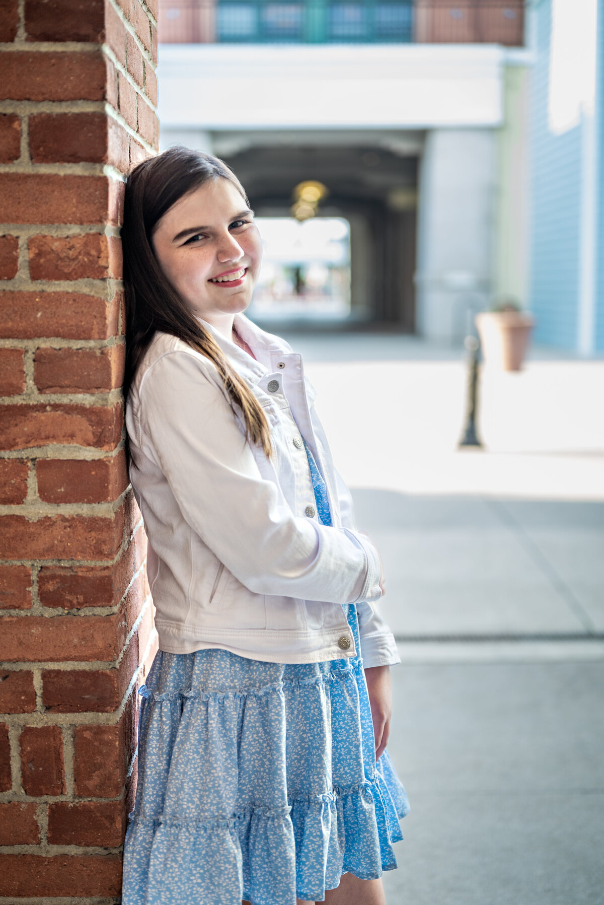 a teen girl leans against a wall and smiles at the camera in downtown Huntsville