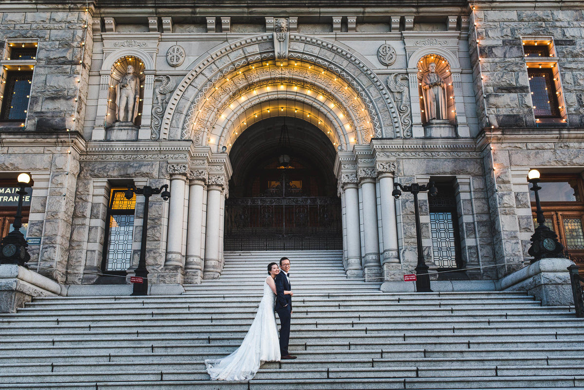 Couple standing on steps of Legislative building in Downtown Victoria
