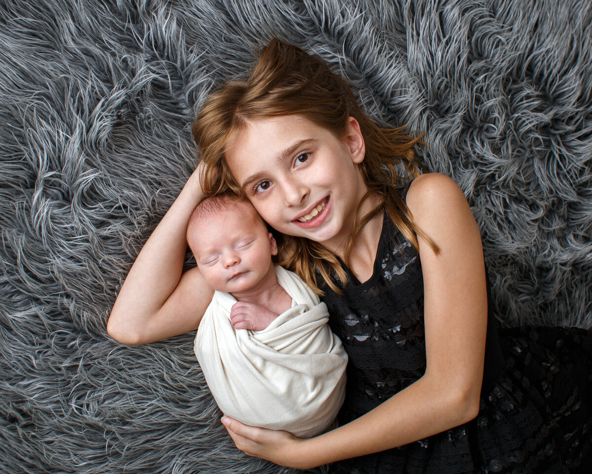 Portrait of an eight year olkd girl with her new baby bother