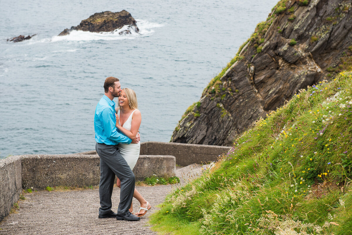 Young couple in summer dress standing on a hill overlooking the beach in Kerry