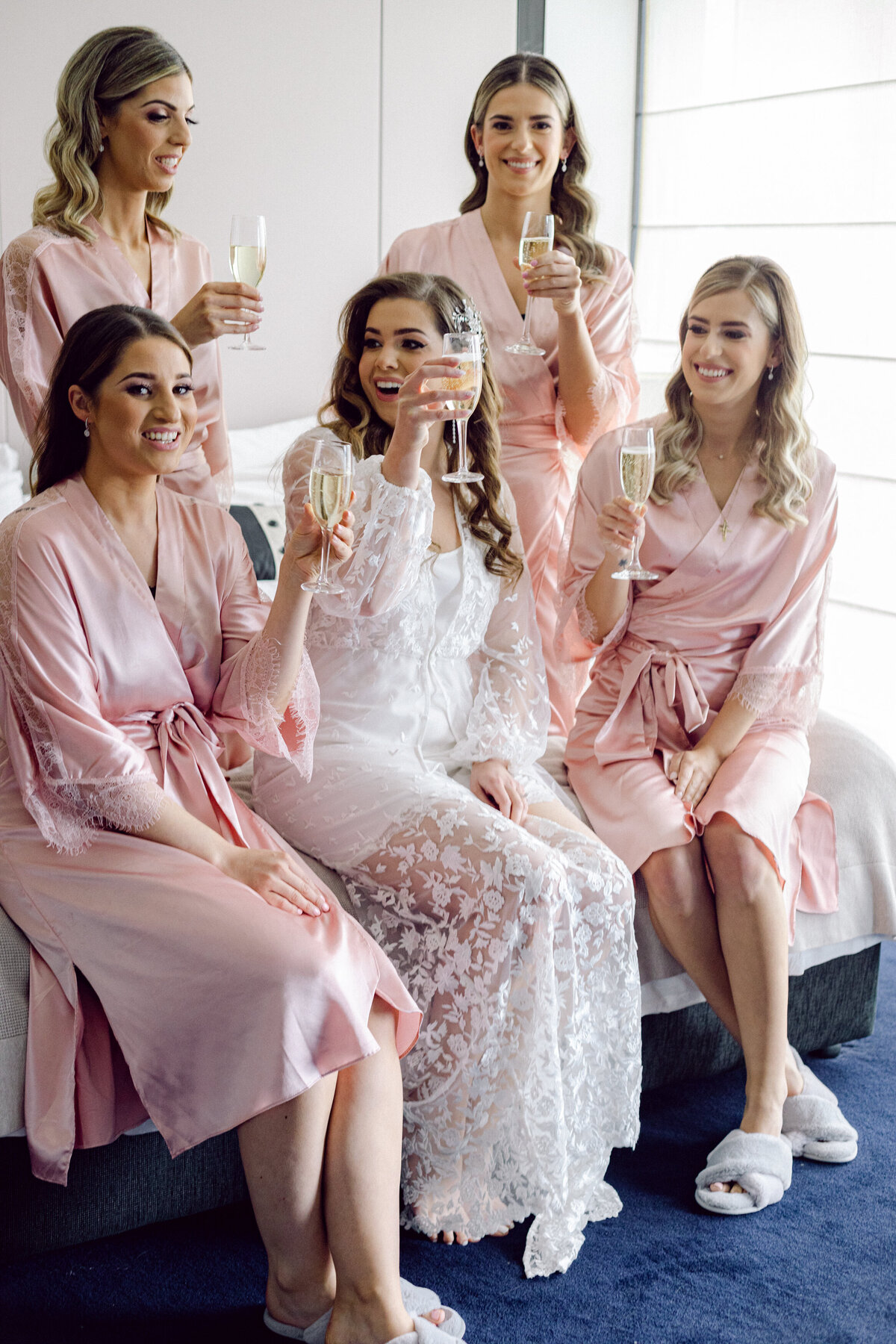 Bride in lace robe + Bridesmaids in pink silk robes + Champagne and wine glasses
