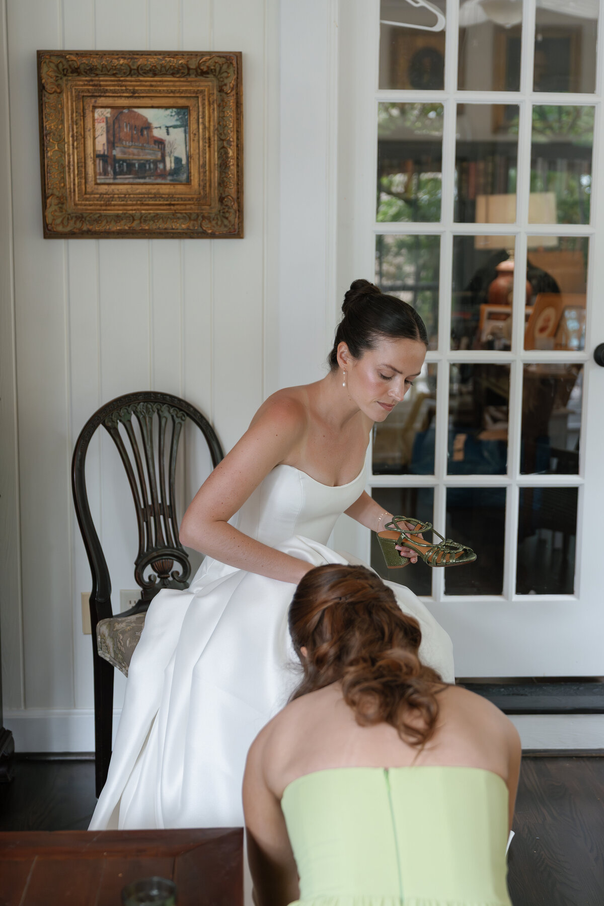 Bridesmaid helping bride put shoes on for wedding in jacksonville fl taken by Shelby Ann Photos