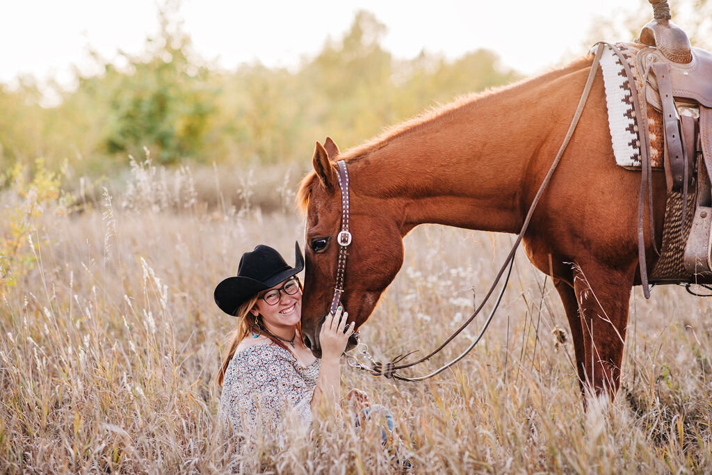 girl sat in long grass with her chestnut horse