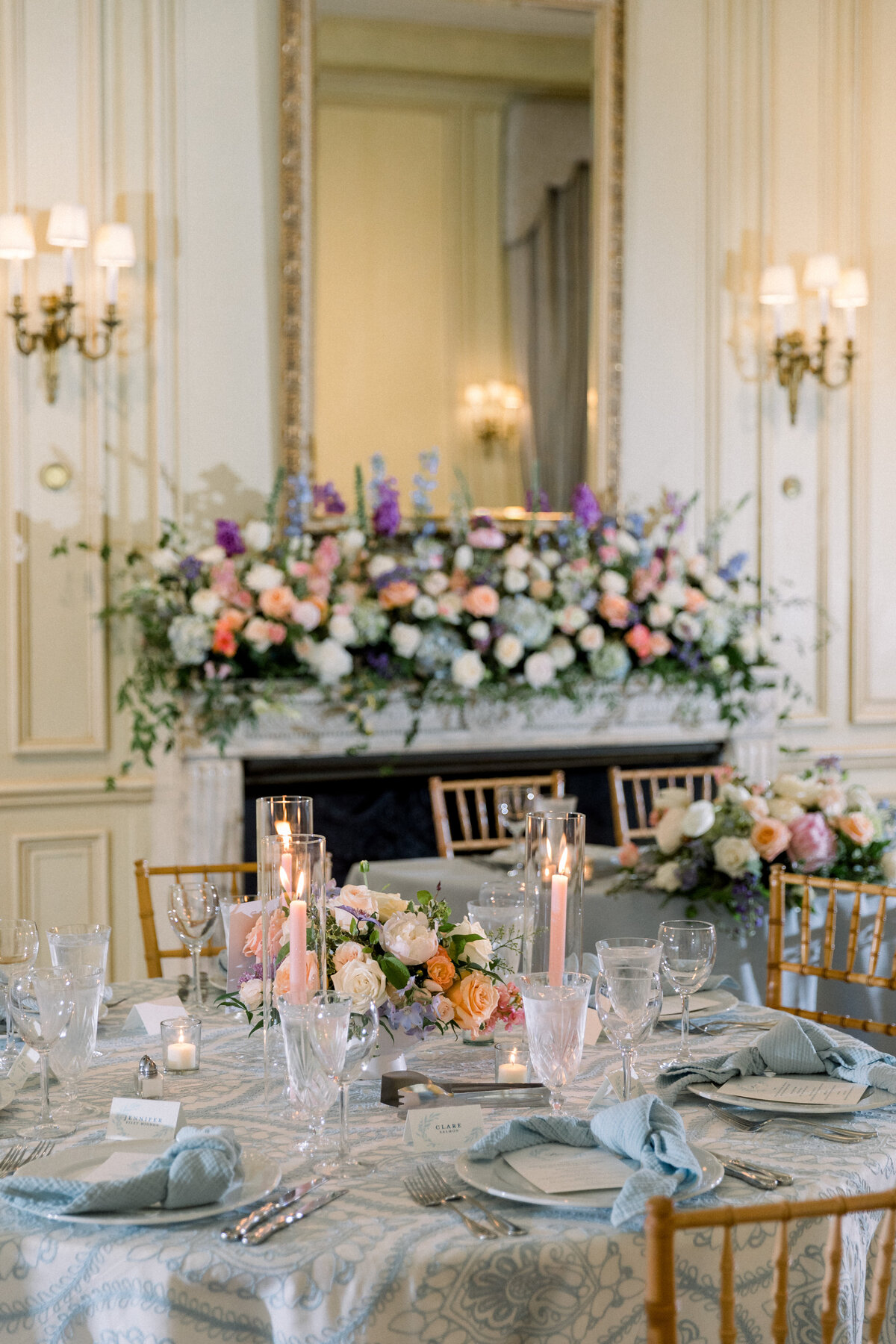 Blue hydrangeas, purple stocks, and pastel garden roses arranged on mantel and wedding guest tables. Elegant floral design for Eastern Shore Maryland wedding venues.