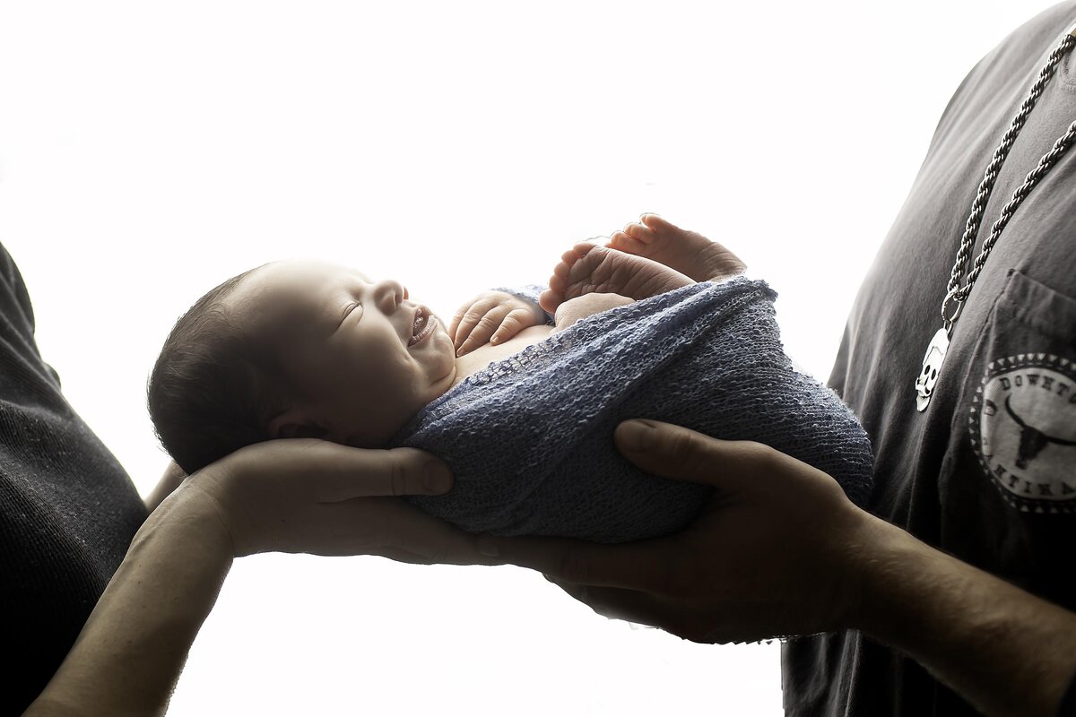Mom and dad’s hands gently cradling their newborn baby, symbolizing love, protection, and the beginning of their journey as a family
