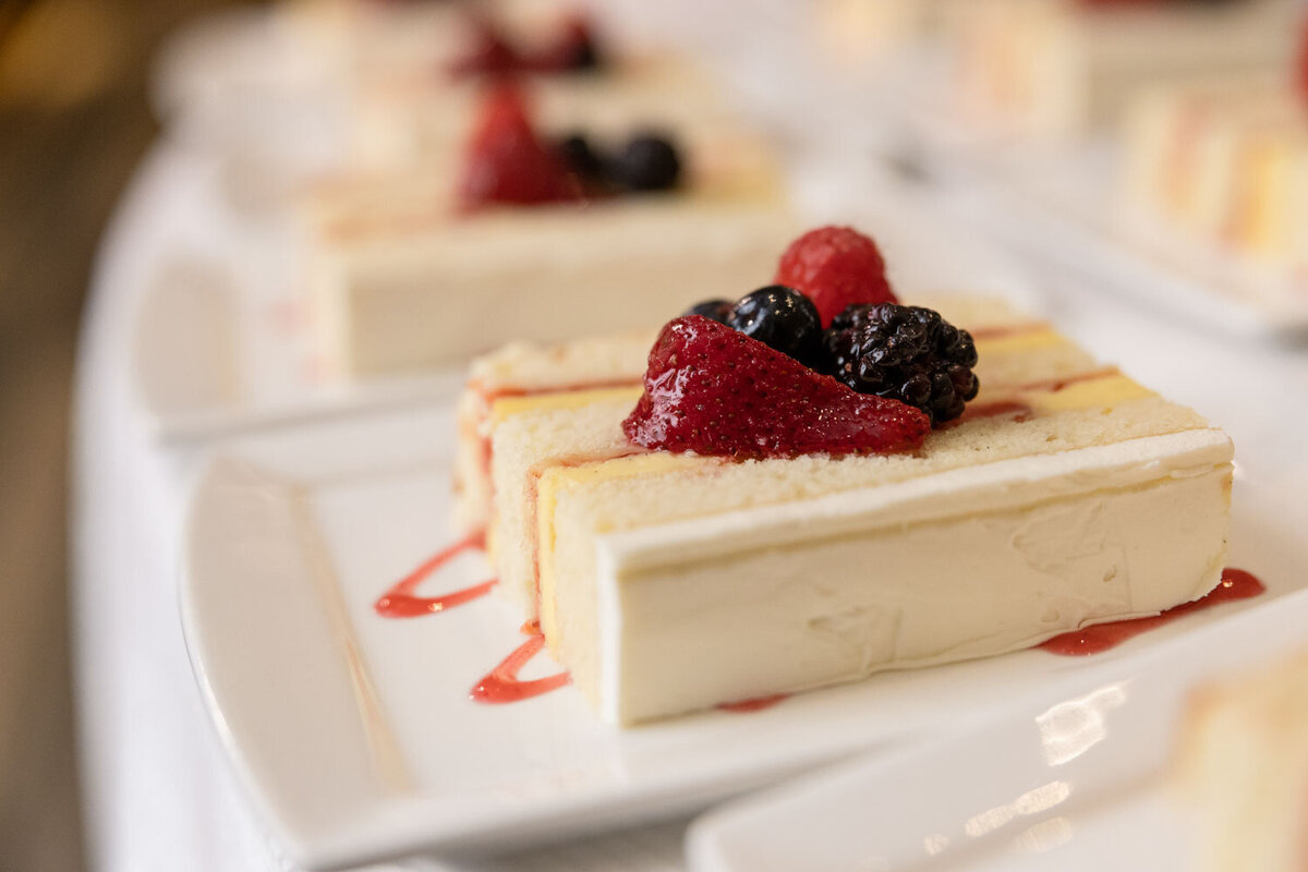 A slice of cake with berries on top on a white plate