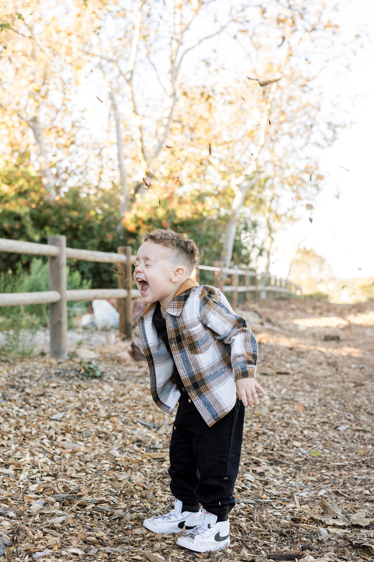 little boy playing in the fall leaves