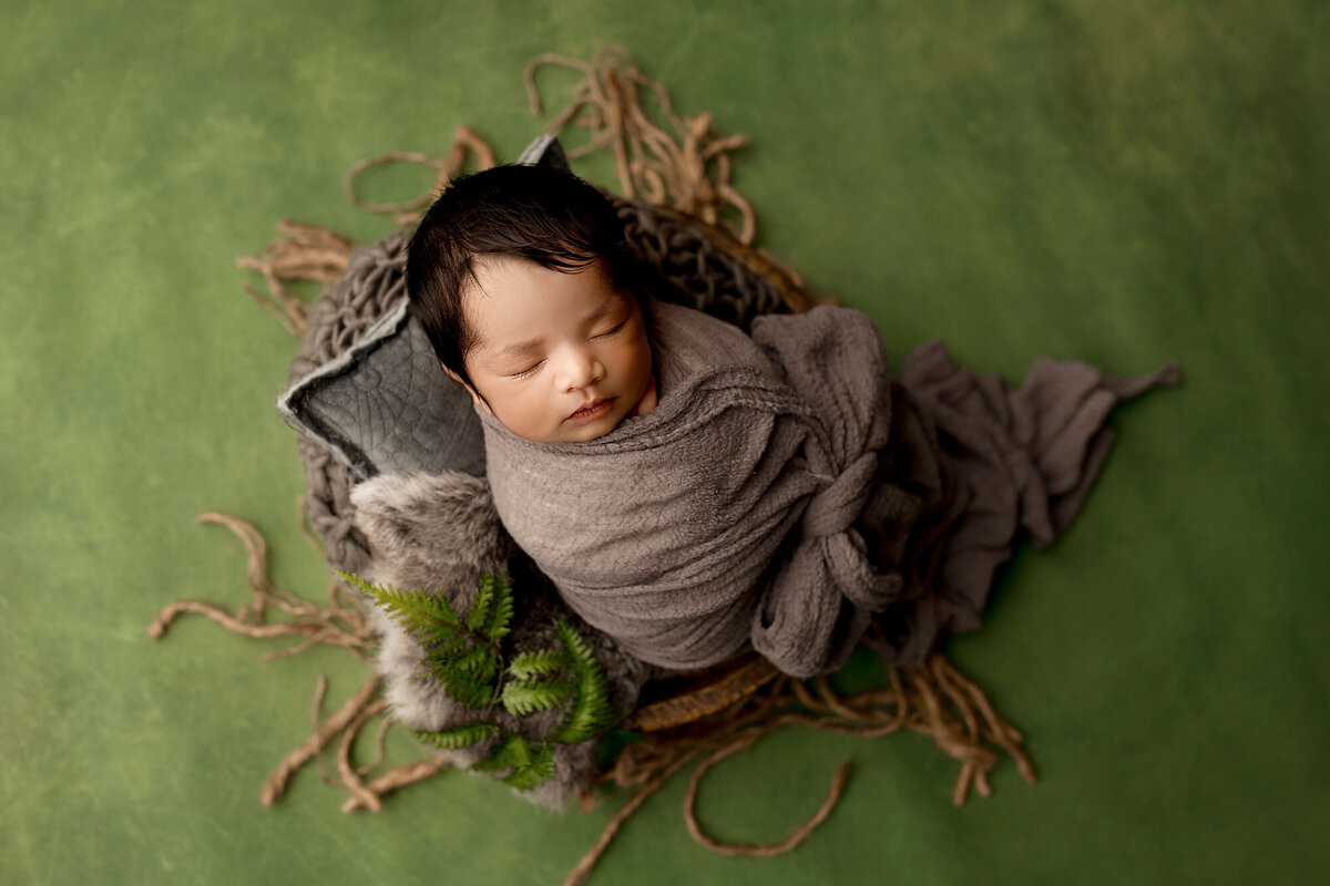 newborn baby boy photographed on a green backdrop natural set up