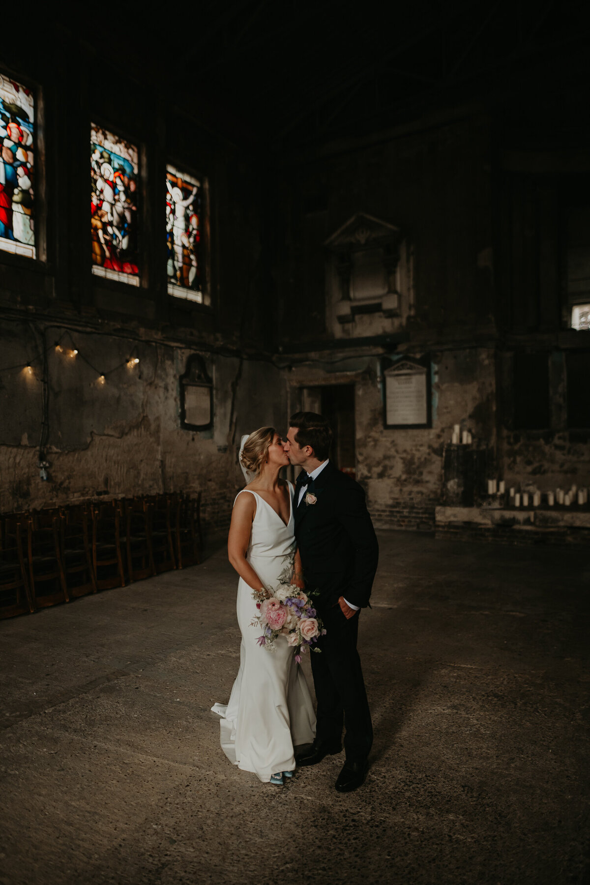 A bride and groom kiss in the middle of an abandoned church in London called The Asylum Chapel. 