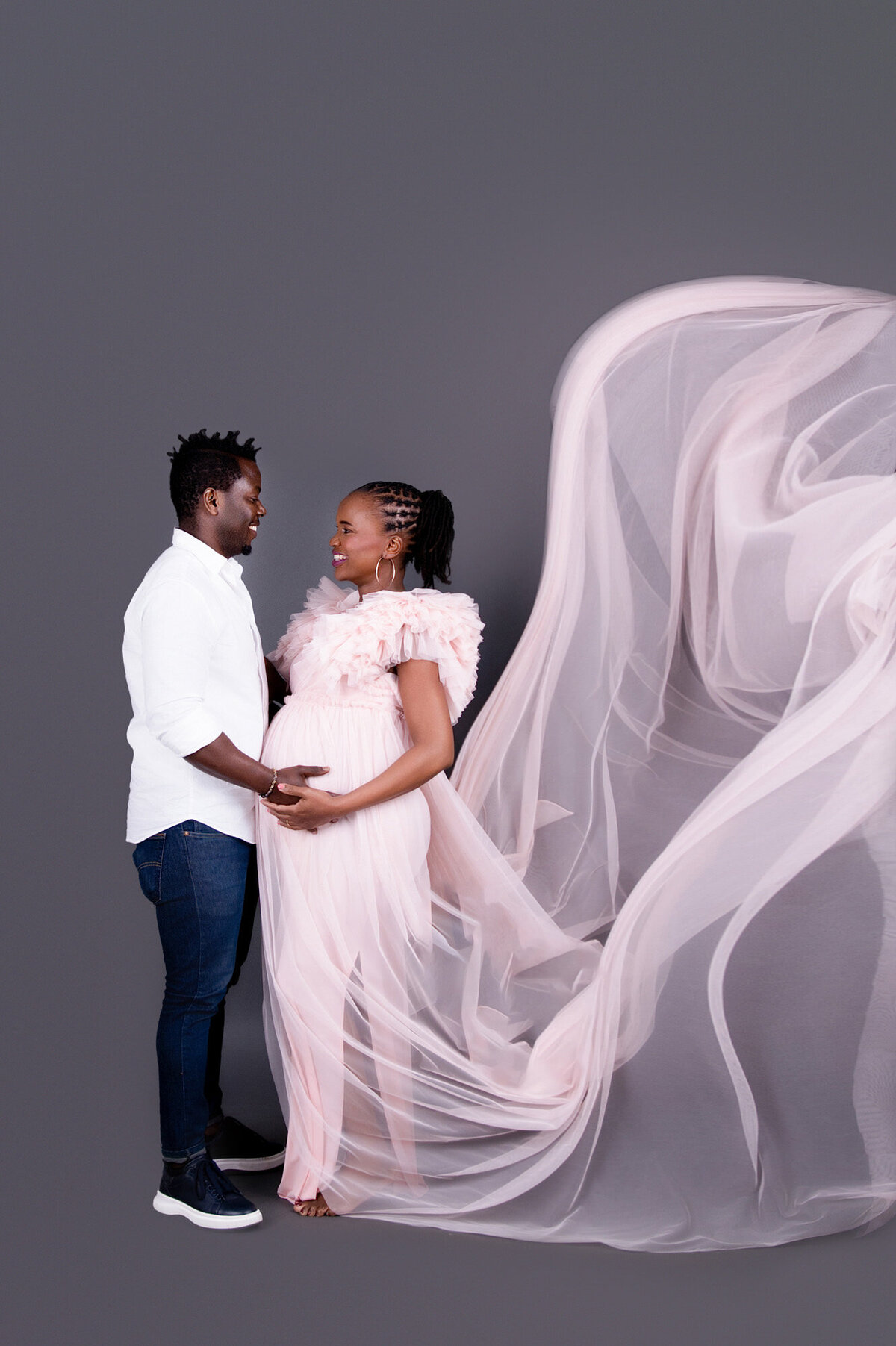 Pregnant mom sitting gracefully in pink flowy gown.