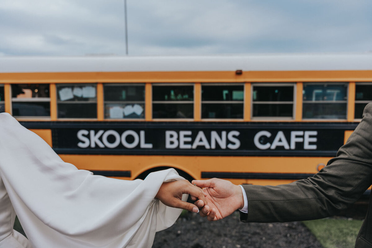 Couple holds hands in front of a school bus 