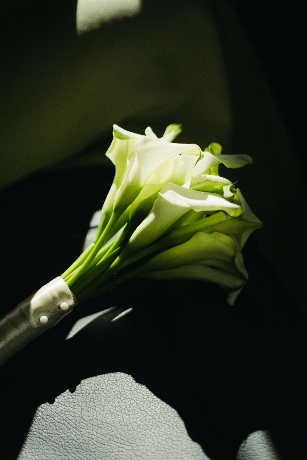 Close-up of elegant white calla lily bouquet in natural sunlight

