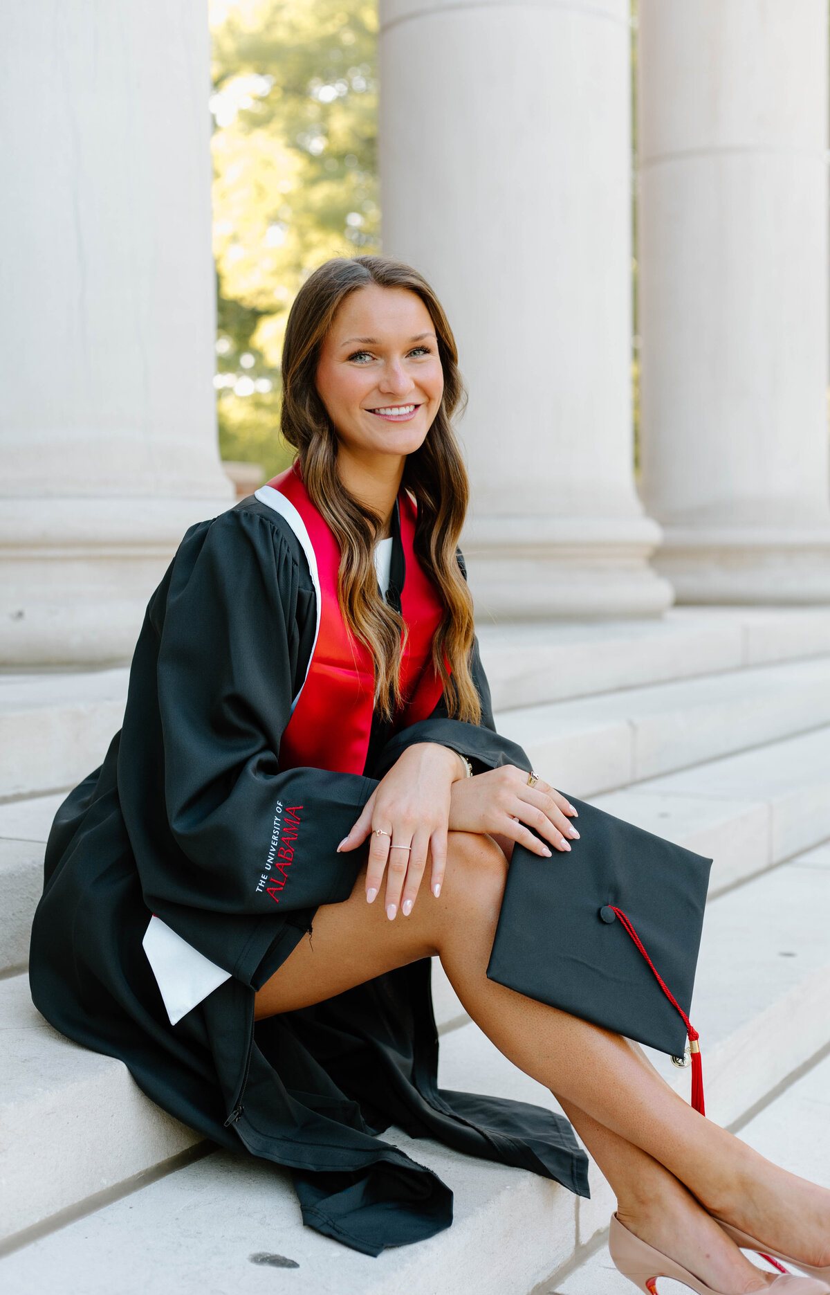 Graduate sitting on the stairs of Reese Phifer in full graduation regalia