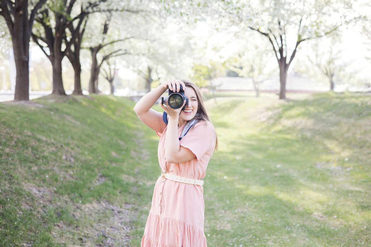 Jessica Bowles, photographer in Las Vegas takes a picture in a  grassy basin with spring blossoms