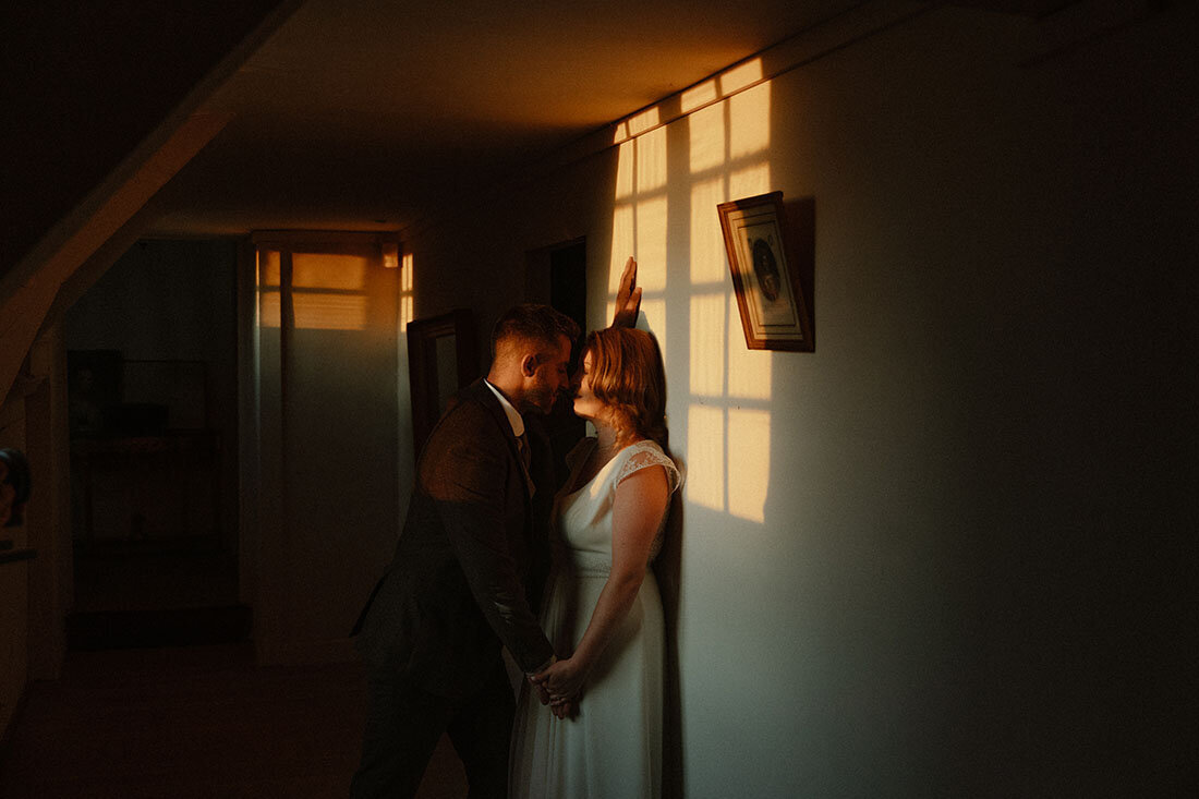 Couple de mariés posant dans un couloir avec jeu de lumières immortalisés par Léa. Photographie de mariage.