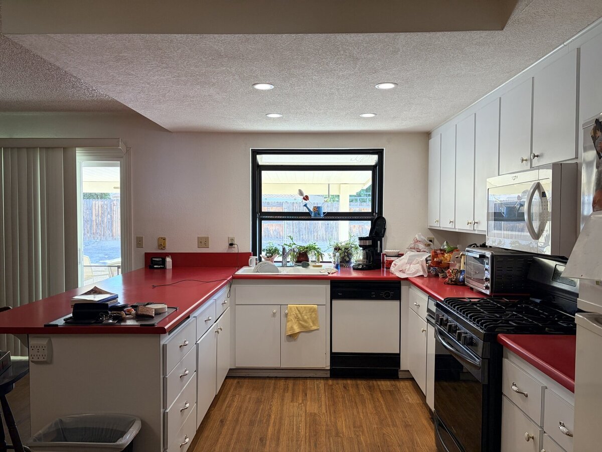 White kitchen cabinets with red countertops in a Wall Works project kitchen