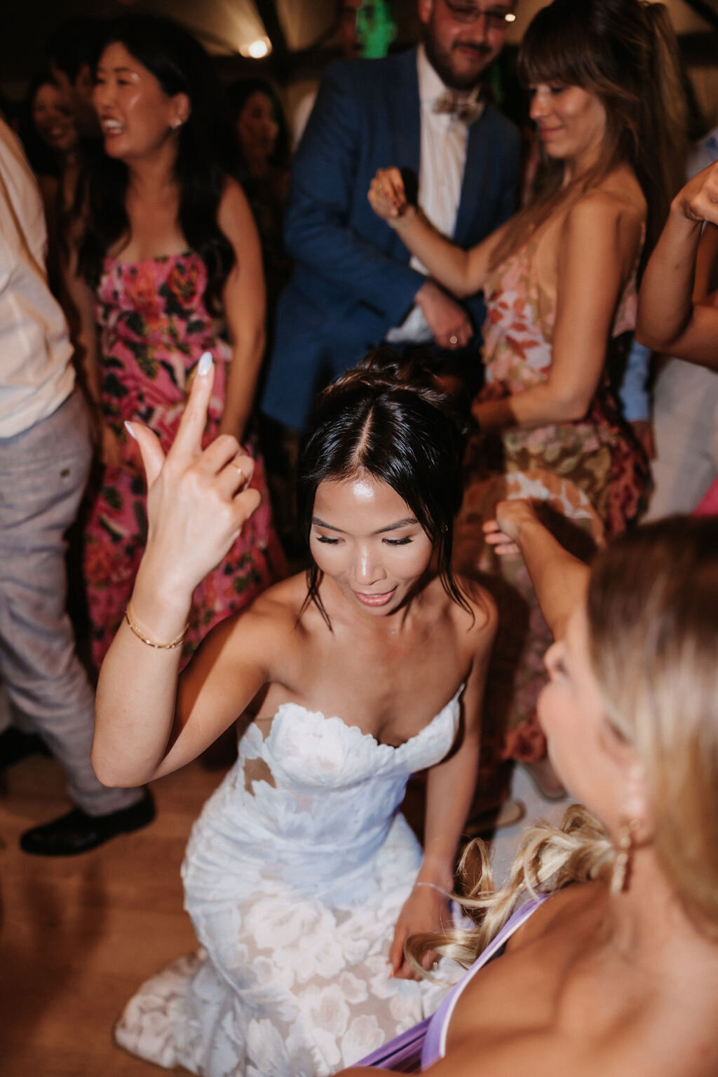 bride crounched down dancing late night reception with her guests
