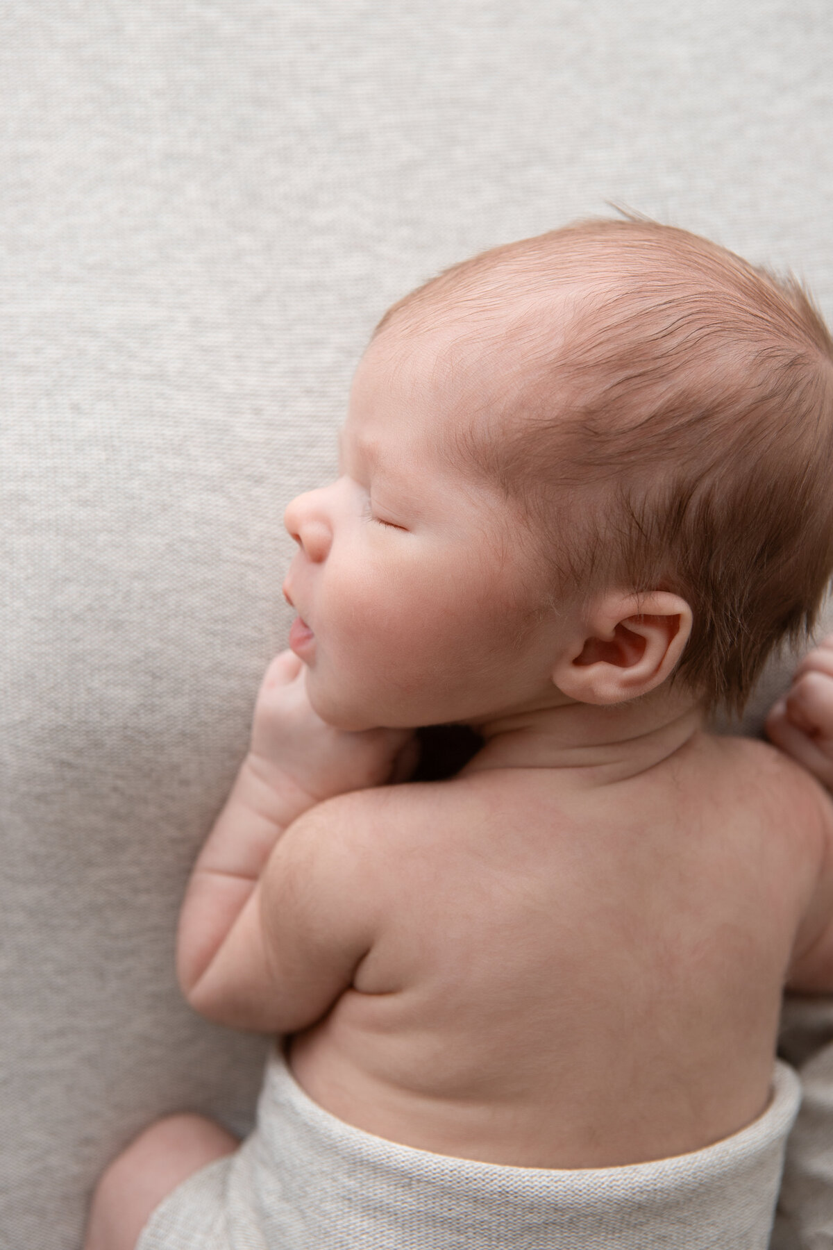 Newborn boy asleep on a grey backdrop posed studio photography