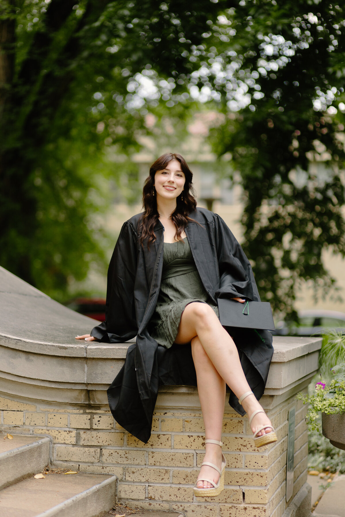 A Colorado State University graduate sits on the steps of the Administration Building in Fort Collins during her senior photo session.