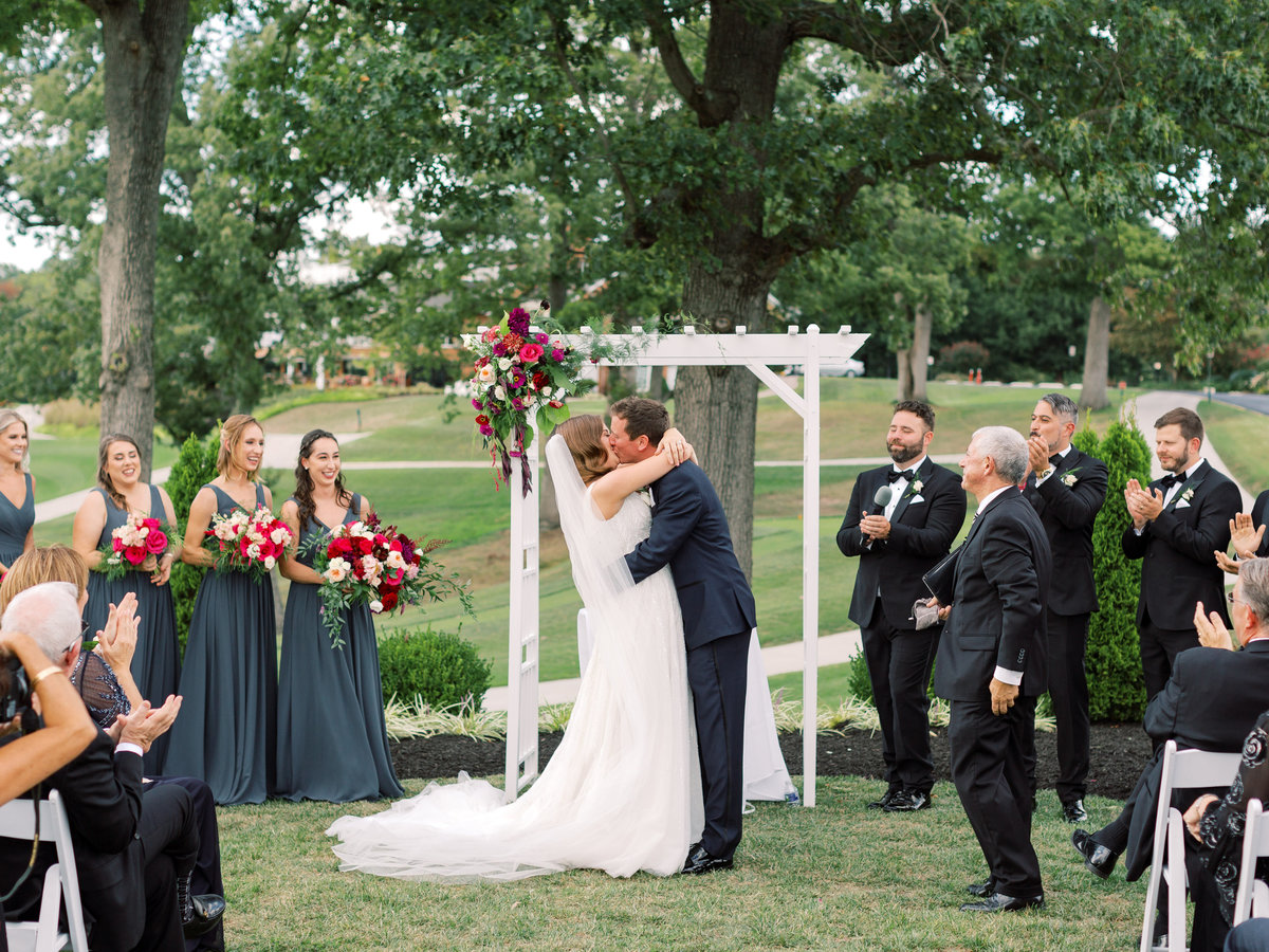 Bride and groom kissing in front of a floral arch in Fairfax VA