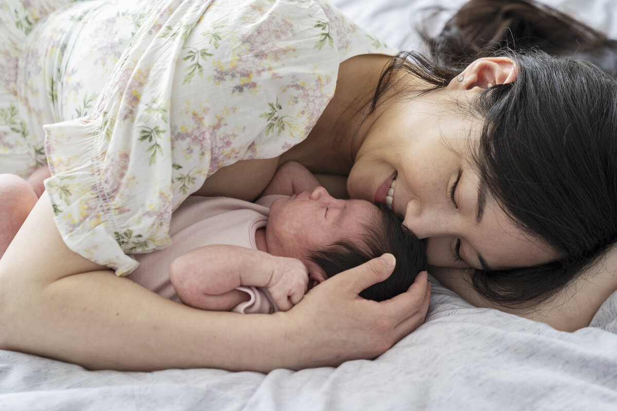A new baby girl sleeps in her mother's arms as they both rest together