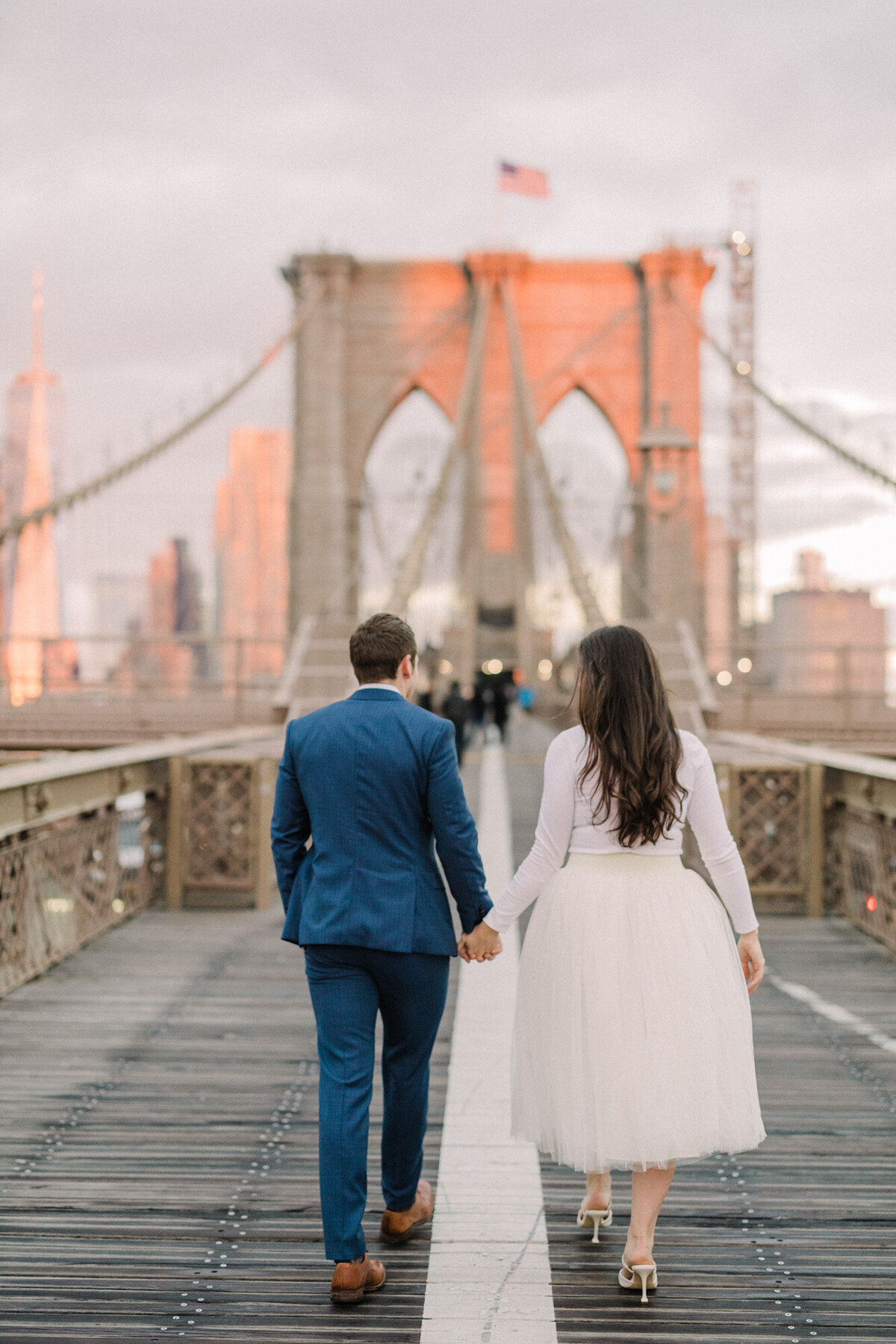 An engagement photo taken at sunrise on the Brooklyn Bridge in New York City