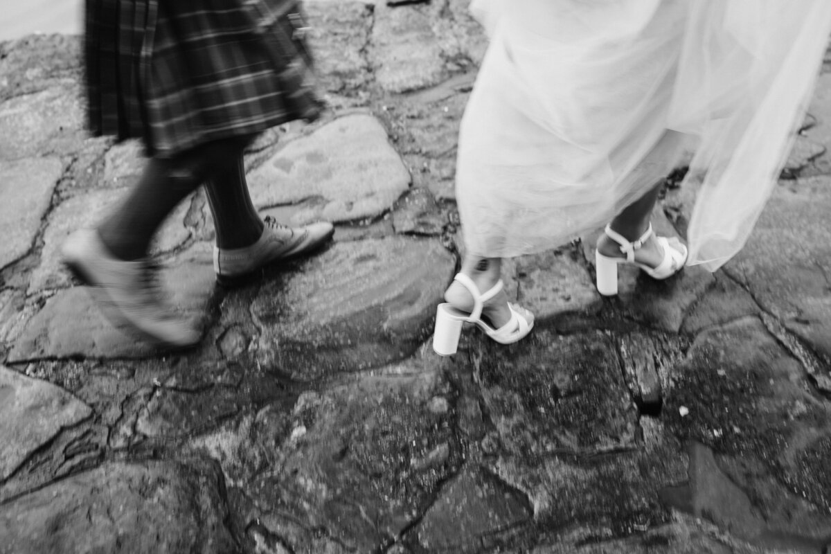 a black and white photo of a bride and groom walking through the cobbled streets of Edinburgh City Wedding Venue