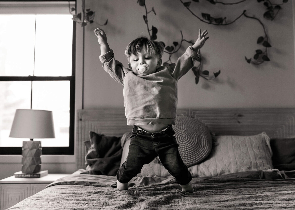 NJ Newborn photographer captures big brother jumping on the bed