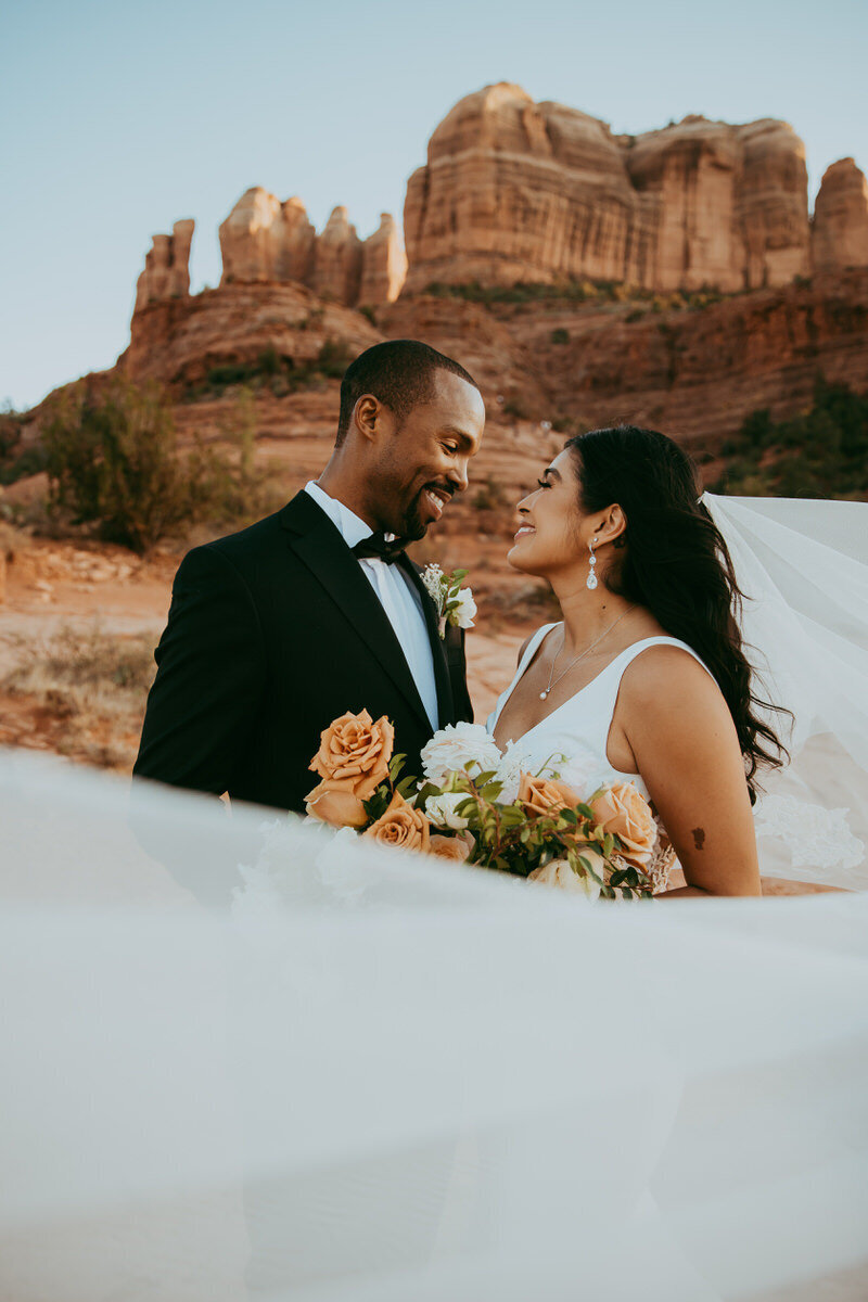 man and woman embrace in front of Catehdra rock in Sedona